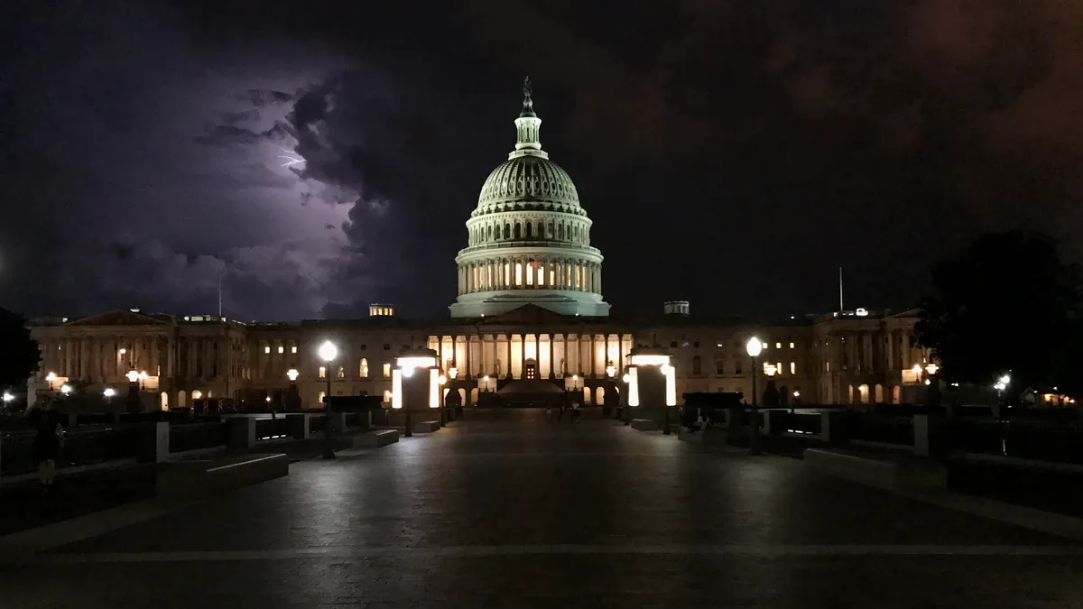 The U.S. Capitol Building at night with lightning in the background.