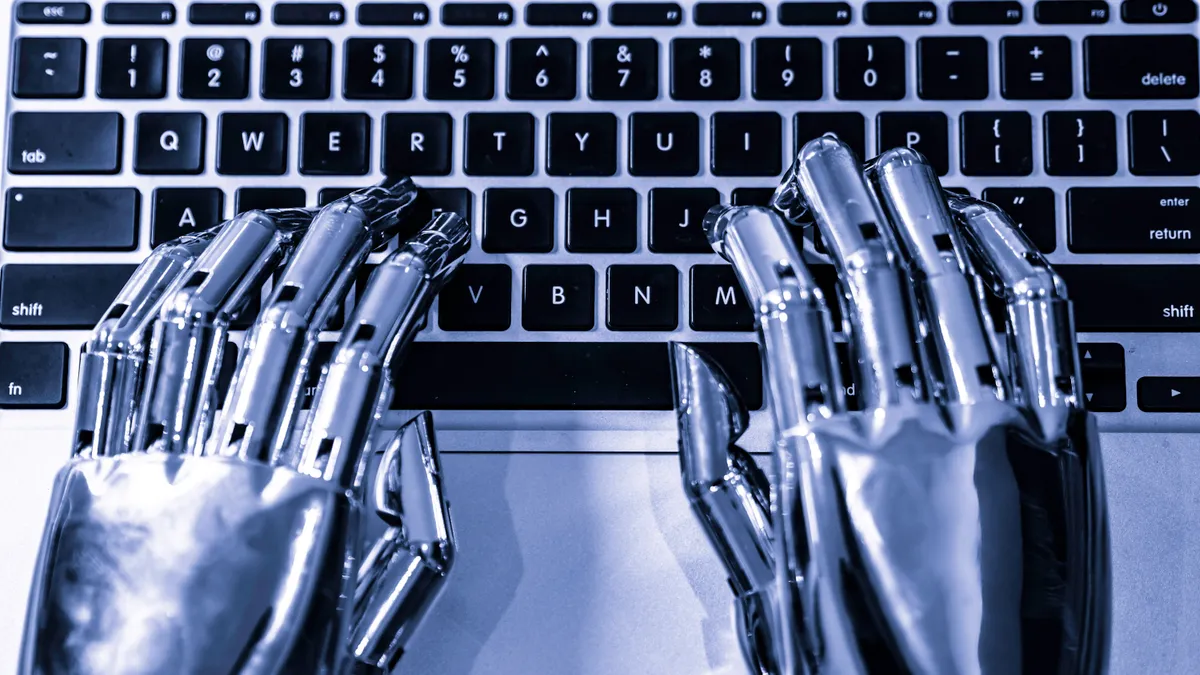 A robot's hands are seen typing on a computer keyboard.
