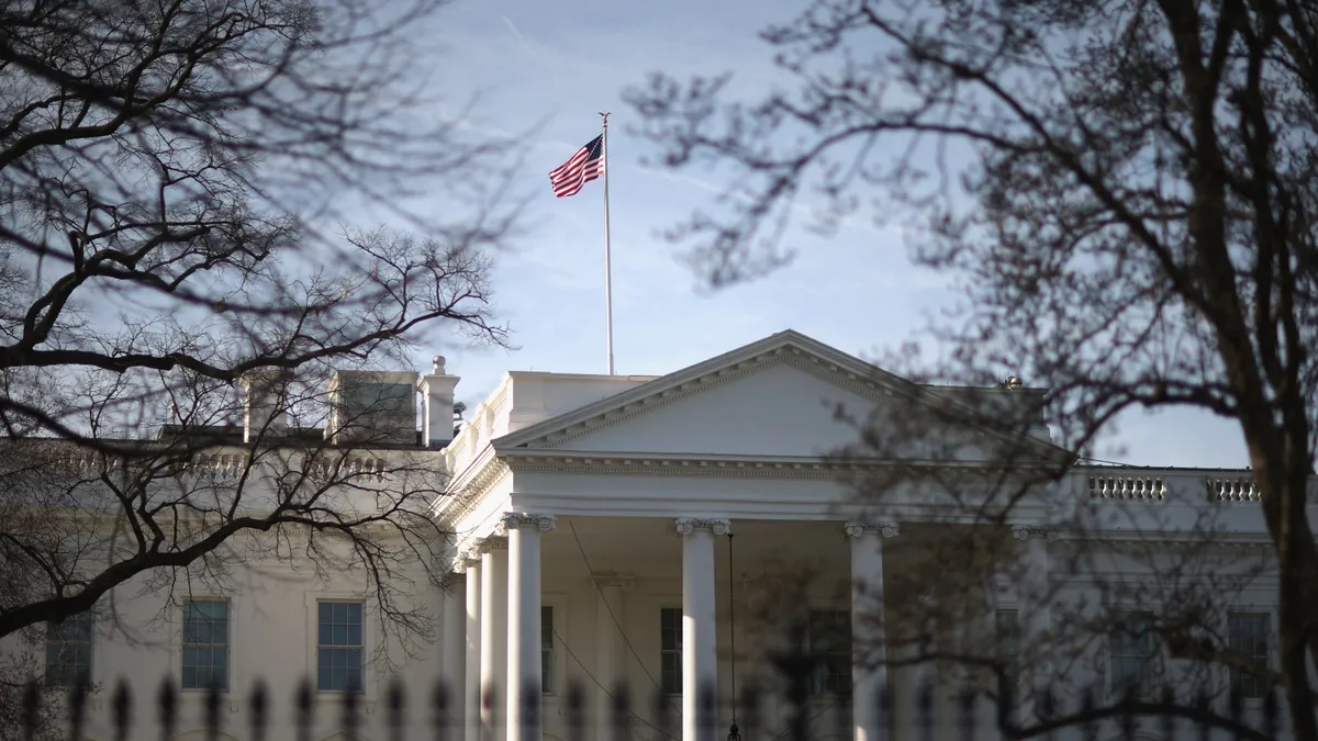The White House exterior in the morning light with an American flag flying.