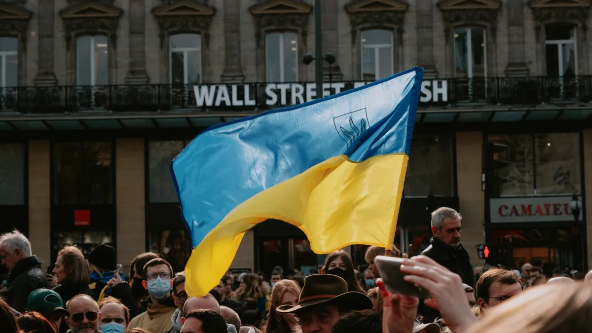 A Ukrainian flag is raised above a protest crowd