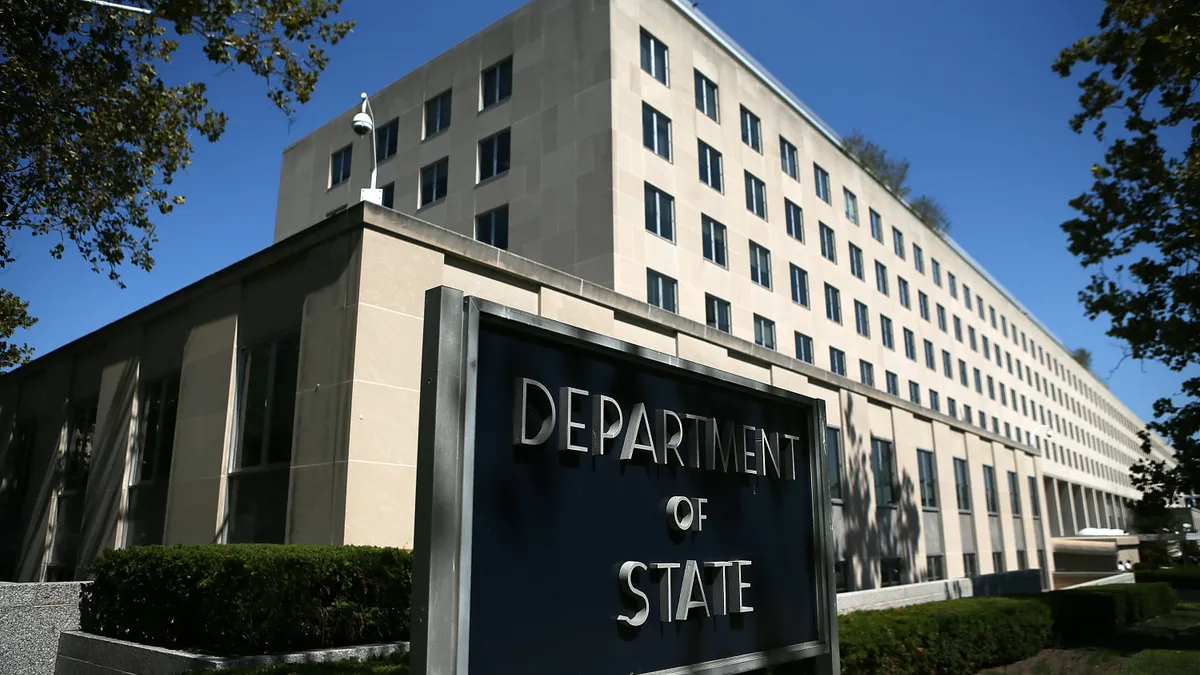 A building showing in the sun with a sign out front that says U.S. State Department.