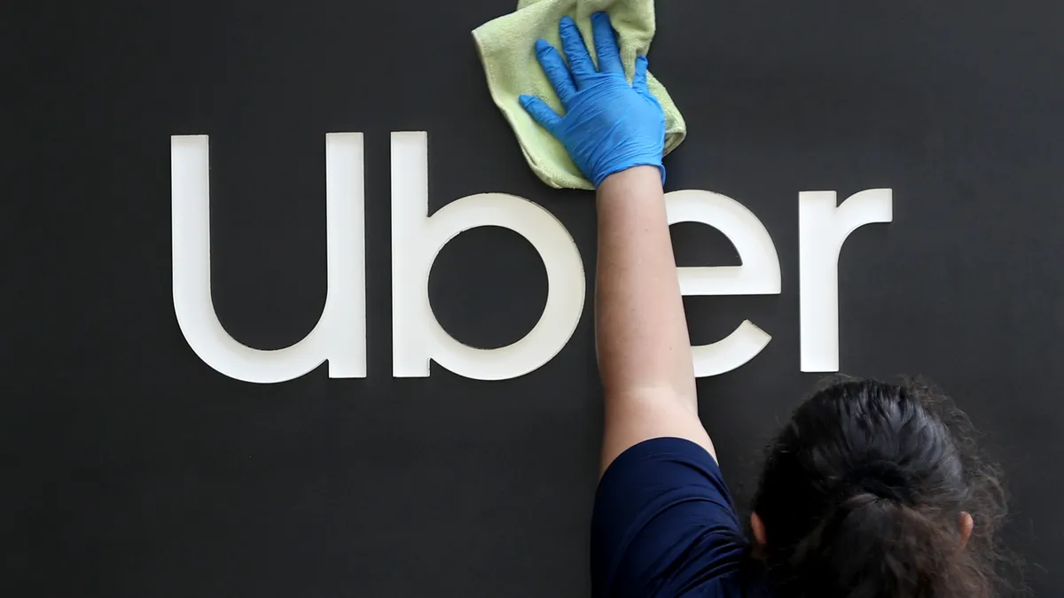 A worker cleans a sign in front of the Uber headquarters on May 18, 2020 in San Francisco, California.