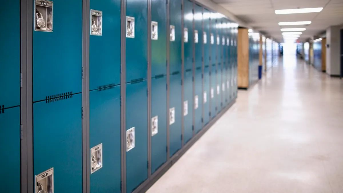 A row of blue lockers in an empty school hallway.