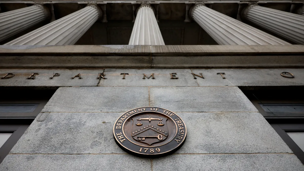 A close up of the Department of Treasury seal on the front of the headquarters with "the Department of Treasury" and "1789" on an outer circle and a shield with the scales of justice up top and a key.